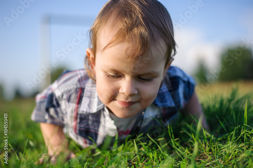 the child lying on the grass on his stomach and looks grass