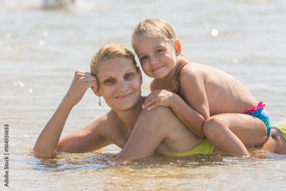 Girl sitting on the mother back, which lies in the sea Girl sitting on the mother back, which lies in the sea