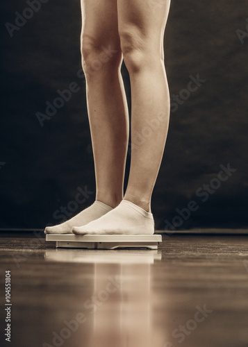 female feet standing on bathroom scales