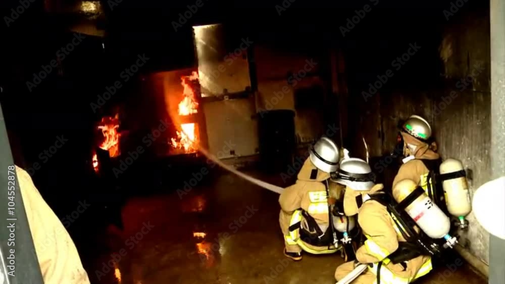 Firefighters battle a practice fire in closed quarters. Firefighters battle a practice fire in closed quarters.