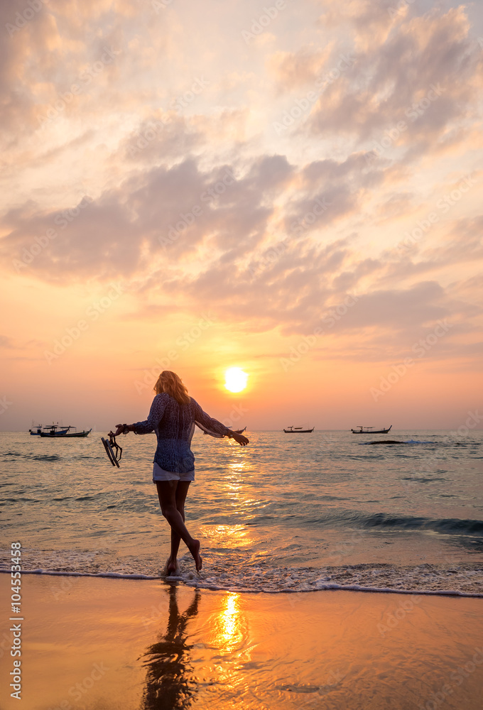 carefree woman dancing in the sunset on the beach