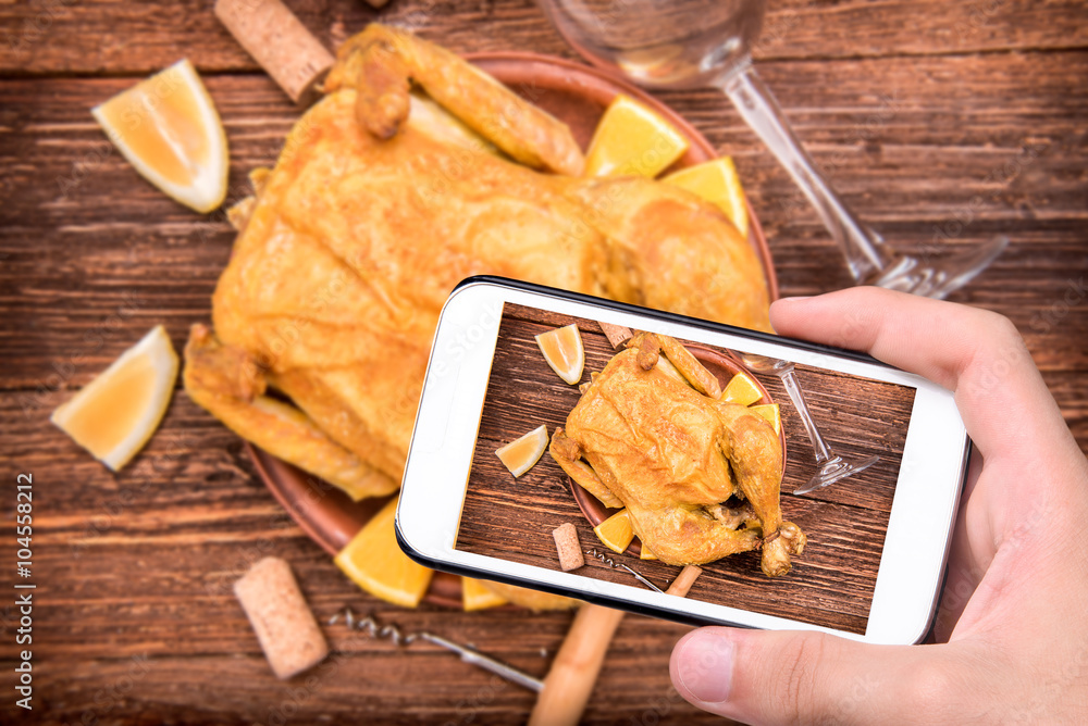 Fototapeta premium Hands taking photo cooked chicken with smartphone.