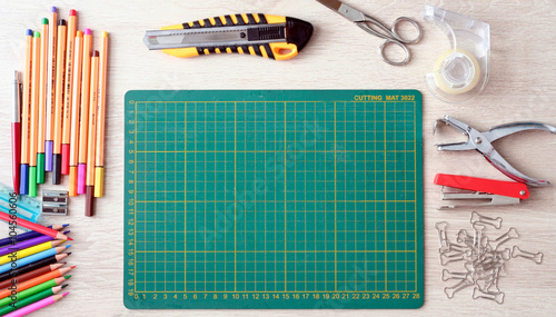 Desktop mockup, top view, with colorful stationery and cutting mat, on wooden background