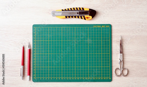 Desktop mockup, top view, with colorful stationery and cutting mat, on wooden background