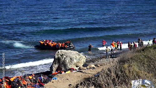 Boat with refugees swam to the shore of the island of Lesvos, Greece. Dangerous and illegal way through the sea from Turkey to the European Union. People on the shore of their encounter to help. photo