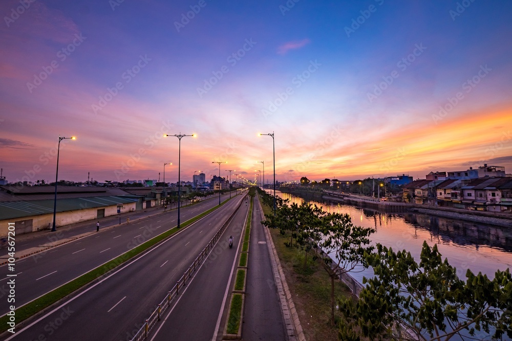 Colourful sunrise on Tau Hu canal and the East-West Highway (Vo Van Kiet street) in Ho Chi Minh City (Saigon). HO CHI MINH, VIETNAM - August 26 2015
