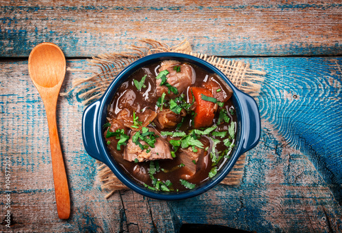 Meat stew with vegetables and herbs on old wooden table