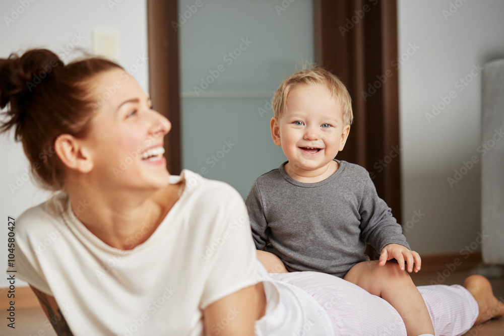 Φωτογραφία Young mother with her one years old little son dressed in pajamas are relaxing and playing in the bedroom at the weekend together, lazy morning, warm and cozy scene