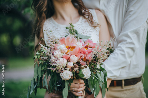 couple holding a bouquet of pink and white peonies and green