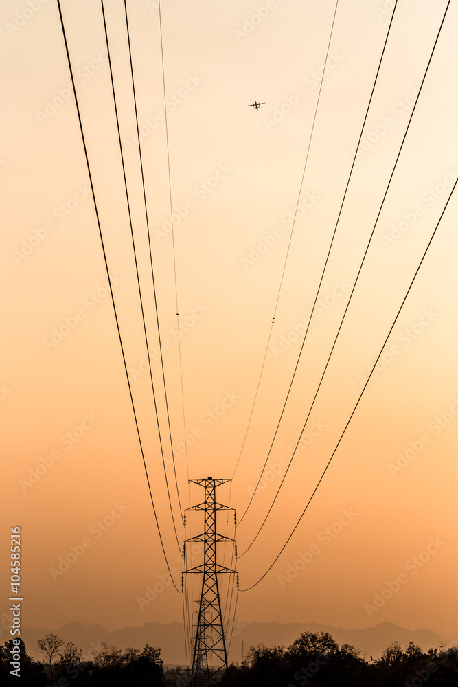 Silhouette of electrical tower with airplan