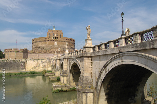 Round tower of the castle and figures of angels on the bridge