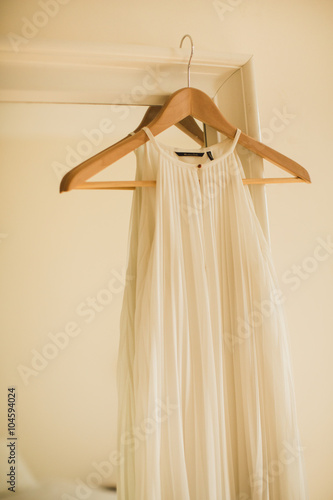 white wedding dress on a hanger hanging on mirror