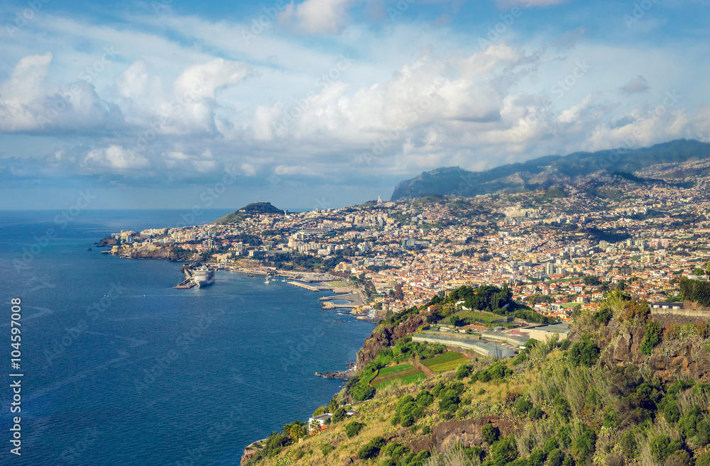 Sunny day in tropical city of Funchal, Madeira, Portugal with blue ocean, few clouds and major cruise ship.