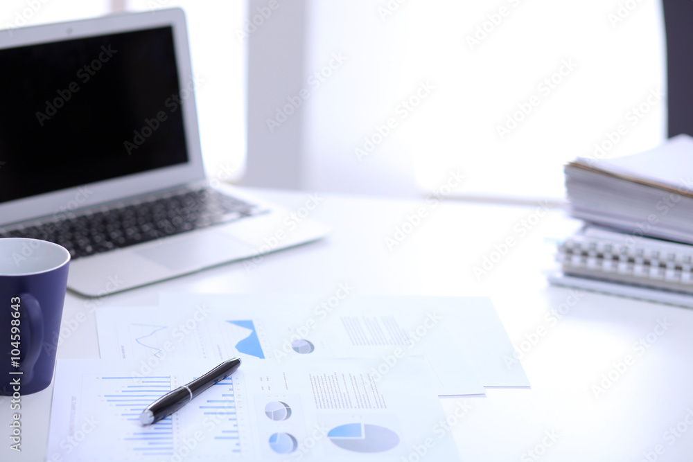 Office workplace with a laptop and financial documents on the light reflecting table Office workplace with a laptop and financial documents on the light reflecting table