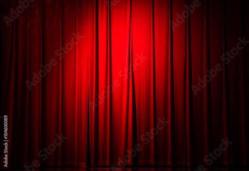 Vintage red velvet curtain with light spots in a concert hall.