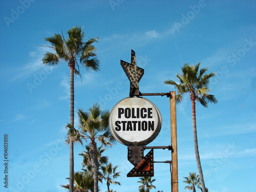 aged and worn vintage photo of police station sign with palm trees