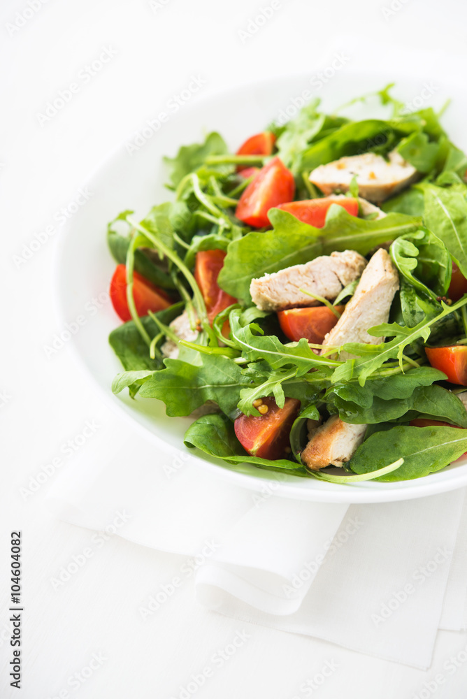Fresh salad with chicken, tomato and greens (spinach, arugula) on white background close up. Healthy food.