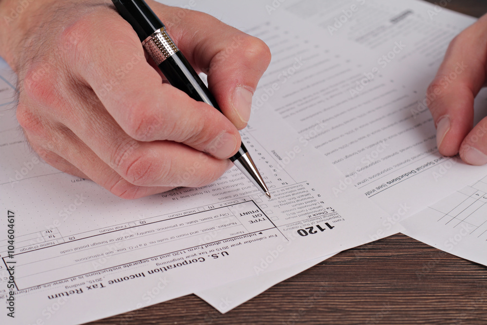 Man filing tax form 1120. United States of America I Corporate Tax Return. Man filing tax form 1120. United States of America I Corporate Tax Return.