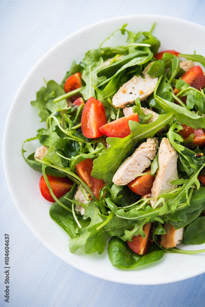 Fresh salad with chicken, tomato and greens (spinach, arugula) on blue wooden background top view. Healthy food. Fresh salad with chicken, tomato and greens (spinach, arugula) on blue wooden background top view. Healthy food.