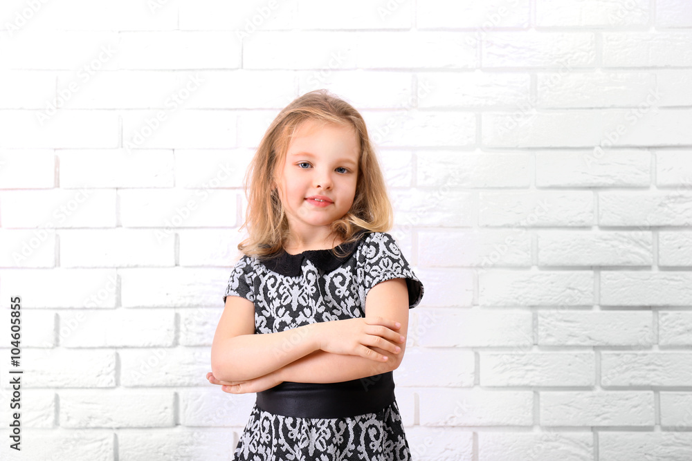 Little girl in dress on a white brick wall background Little girl in dress on a white brick wall background