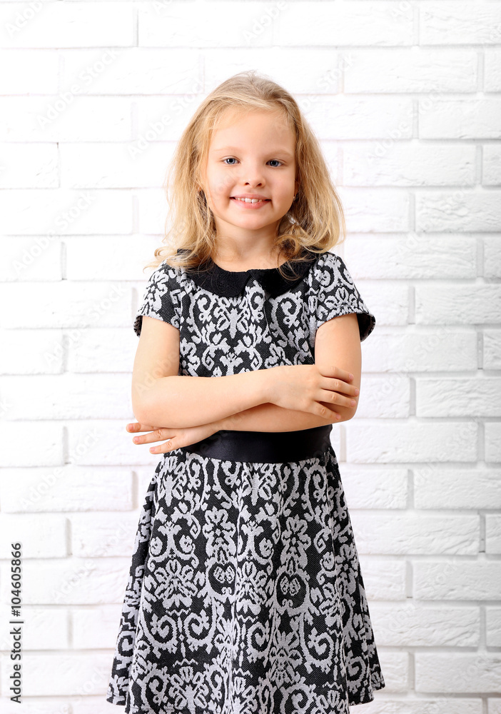 Little girl in dress on a white brick wall background