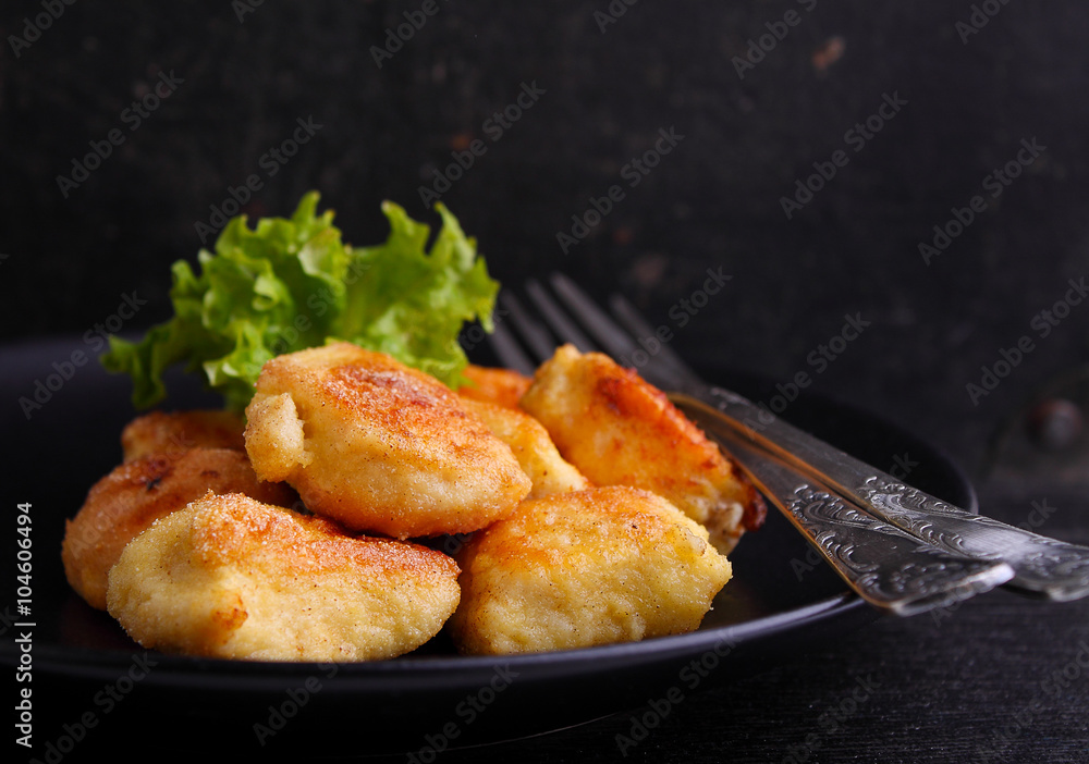 chicken nuggets in a black plate on a black background