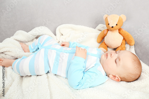 Adorable baby sleeping with teddy bears on sofa in the room, close up