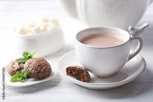 Cup of cocoa with chocolate chip cookies and mint on light background