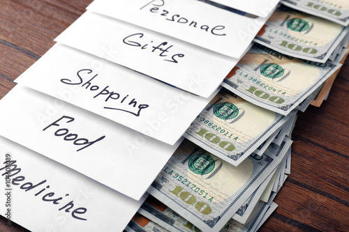 Distribution of money, financial planning, dollars in envelopes on wooden table background