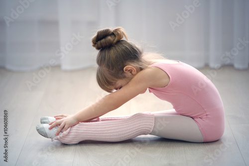 Obraz na plátně Little cute girl in pink leotard making new ballet movement at dance studio