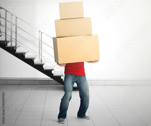 Man holding pile of carton boxes in the room