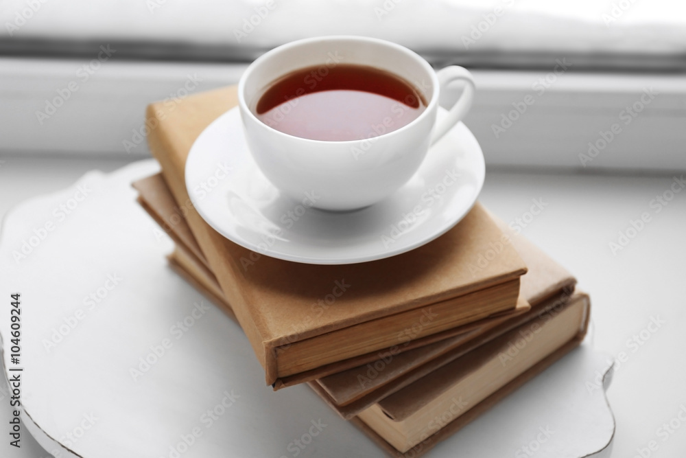 Cup of tea, book and warm knitted plaid on windowsill, close up Cup of tea, book and warm knitted plaid on windowsill, close up