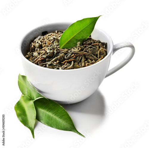 Cup with dry tea and green leaves, isolated on white