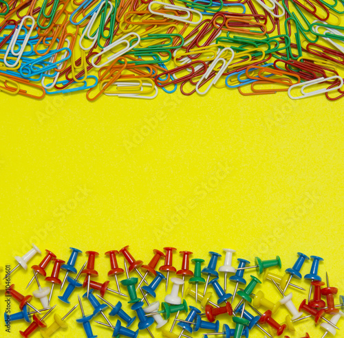 Colorful paper clip and pin isolated on yellow background