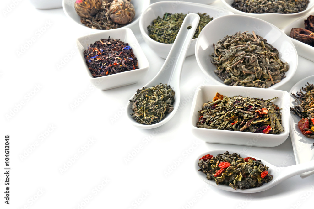 Variety of dry tea in bowls and spoons isolated on white Variety of dry tea in bowls and spoons isolated on white
