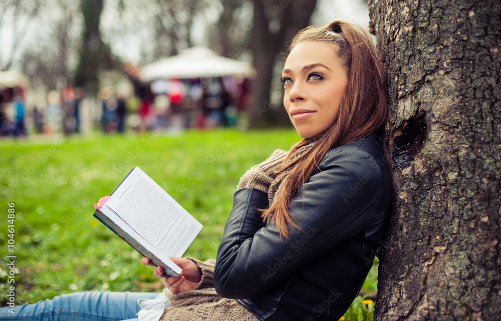 Fototapeta premium Young woman reading book / Closeup of a beautiful young woman reading book at park