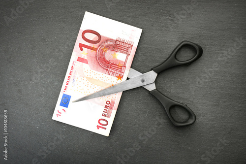 Concept of spending money - scissors cut money on black background