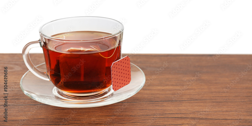 Glass cup with tea bag on wooden table over white background Glass cup with tea bag on wooden table over white background
