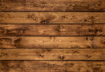 Medium brown wood texture background viewed from above. The wooden planks are stacked horizontally and have a worn look. This surface would be great as design element for a wall, floor, table etc…