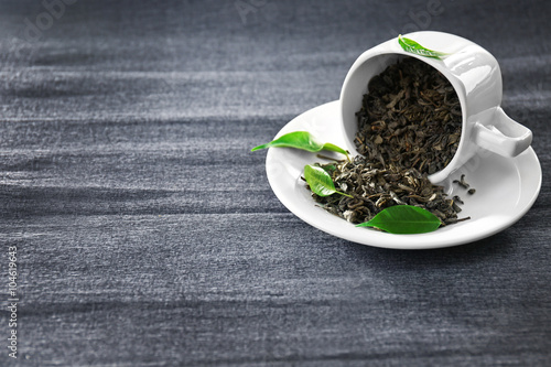 Photography Granulated tea with green leaves in tea-set on grey background