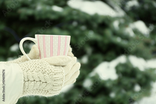 Female hands holding cup of hot drink at the winter park