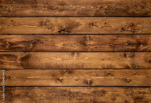 Medium brown wood texture background viewed from above. The wooden planks are stacked horizontally and have a worn look. This surface would be great as design element for a wall, floor, table etc…