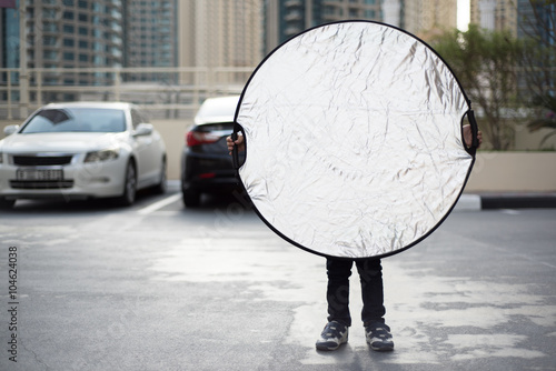 Funny Little Photographer's Assistant is Holding a Silver Reflector