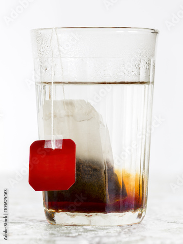 Foto Faceted glass of boiled water and tea bag