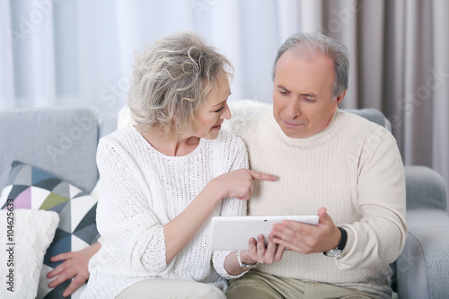 Happy mature couple using t...