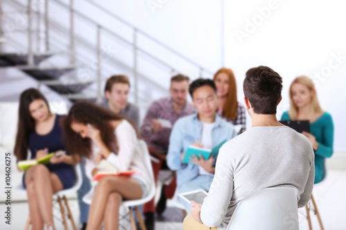 Young man sitting back in front of people and woman talking on the smart phone at the office meeting