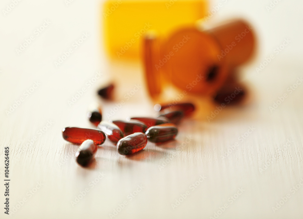 Different Capsules Spilled From Orange Pill Bottles On Wooden Table different-capsules-spilled-from-orange-pill-bottles-on-wooden-table