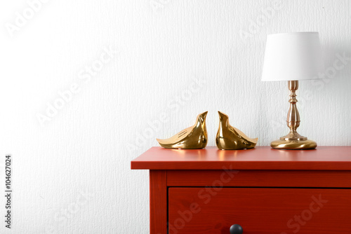 Billede på lærred Room interior with red wooden commode and lamp on light wall background