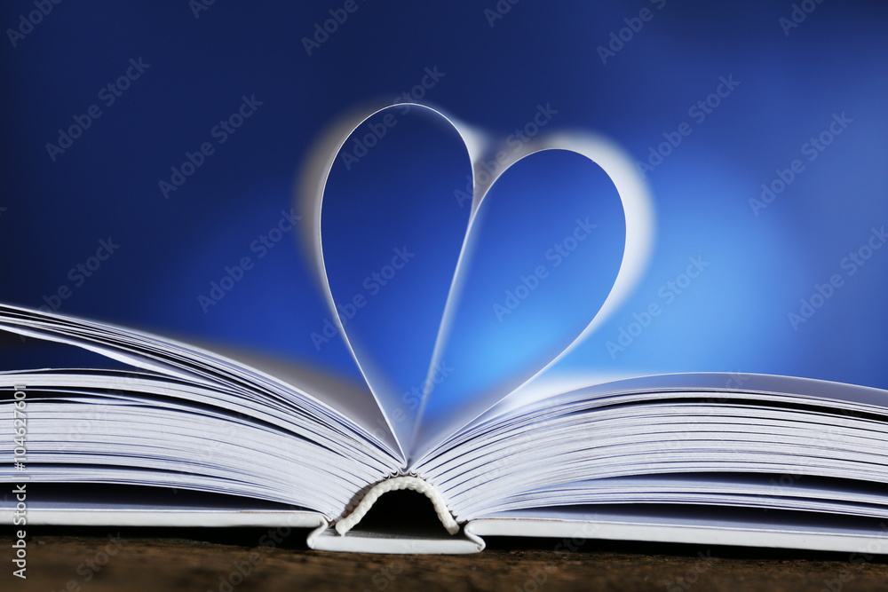Heart from book pages on blue blurred background Heart from book pages on blue blurred background