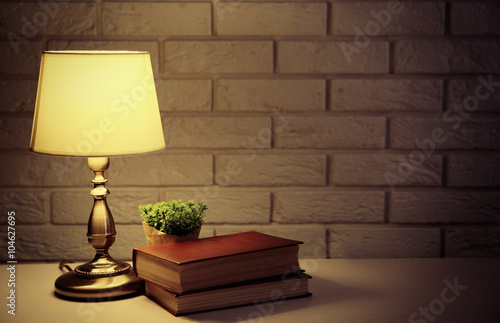 Night lamp and books on the desk on white brick wall background